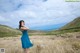 A woman in a blue dress standing in a field.