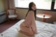 A woman sitting on a bed in a hotel room.