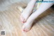 A woman's feet with red nail polish on a wooden floor.