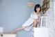 A woman in a white dress sitting on top of a dresser.