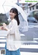 A woman holding an umbrella standing in the middle of a street.