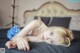 A woman laying on a bed with a blue flower in her hand.