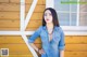 A woman standing in front of a wooden wall.