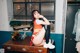 A woman sitting on top of a wooden desk.