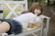 A young woman in a school uniform laying on a bench.