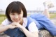 A young woman laying on a stone wall with her legs crossed.