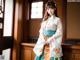 A woman in a kimono standing in front of a window.