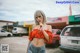 A woman in a red top and denim shorts smoking a cigarette.