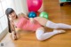 A woman in a pink leotard and white tights laying on the floor.