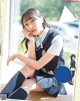 A woman in a school uniform sitting on the floor.