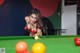 A woman in a red bikini playing pool.